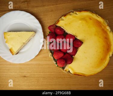 Cheescake con diverse fragole su sfondo di legno. Vista dall'alto Foto Stock