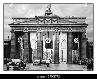 OLIMPIADI DI BERLINO Vintage 1936 Parata della porta di Brandeburgo Berlino Germania nazista con bandiere della Swastika nazista accanto ai Giochi Olimpici ufficiali Bandiere Berlino porta di Brandeburgo Germania nazista Parata con Adolf Hitler che conduce attraverso la porta di Brandeburgo sulla strada per le cerimonie di apertura dei Giochi Olimpici. Berlino, Germania, 1 agosto 1936. Foto Stock