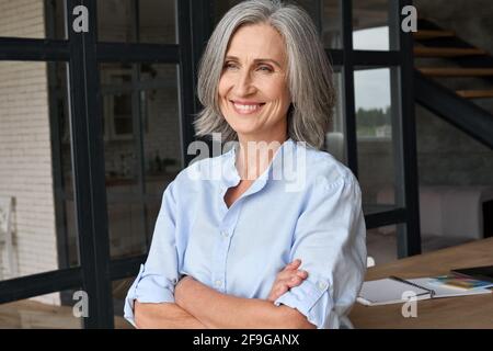Ritratto di sorridente donna d'affari in piedi in ufficio domestico. Foto Stock