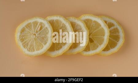 Pezzi di limone, limone affettato a fette su uno sfondo di colore albicocca Foto Stock