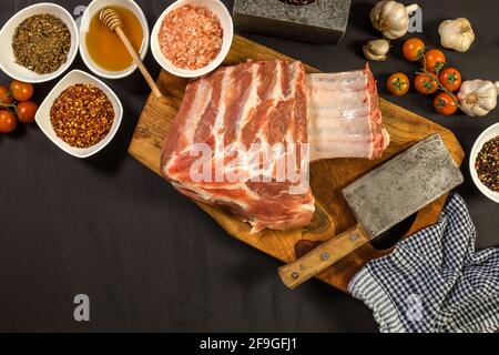 Costolette di maiale crude con spezie. Carne cruda sulla tavola della cucina. Preparazione di marinata di miele e peperoncini. Barbecue estivo. Foto Stock