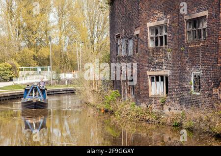 Canale narrowboat sul canale Trent e Mersey passando il Vecchio derelict Kensigton & Price lavori di ceramica e magazzino in Longport Stoke on Trent Foto Stock