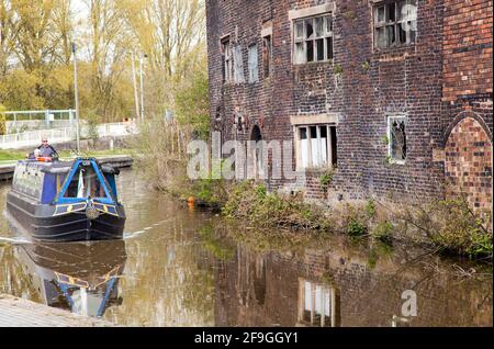 Canale narrowboat sul canale Trent e Mersey passando il Vecchio derelict Kensigton & Price lavori di ceramica e magazzino in Longport Stoke on Trent Foto Stock