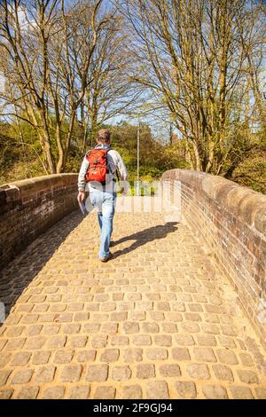 Uomo zaino in spalla a piedi su un vecchio canale carrello ponte cavallo Sopra il canale Trent e Mersey a Kidsgrove Stoke on Trent Staffordshire Foto Stock