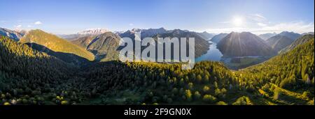 Vista aerea, panorama montano con lago Plansee al sole del mattino, atmosfera mattutina, sinistra Zugspitzmassiccio, Alpi Ammergau, Reutte, Tirolo, Austria Foto Stock