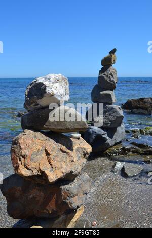 Pile di massi su una spiaggia a Fuengirola, Spagna - sculture di Art Rock di quattro o cinque grandi pietre, contro il cielo blu e il mare calmo. Foto Stock