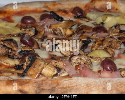 particolare di una pizza con pomodoro, mozzarella, olive, carciofi e funghi Foto Stock