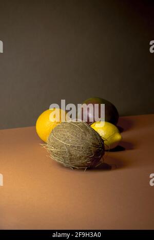 Limone, cocco, mango, arancio su uno sfondo a due colori. Concetto di frutta tropicale minimo. Colori alla moda marrone e arancione. Estate vibes idea. Foto Stock