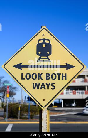 Guarda entrambe le direzioni con una freccia a due punte e un treno sulla pista ferroviaria in giallo e nero. Questo cartello di avvertimento si trova a Edmonds, Snohomish County Foto Stock