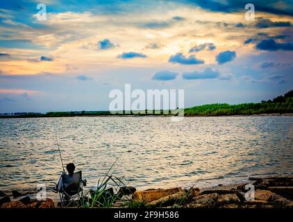 Un uomo pesca al tramonto, 7 luglio 2012, a Bayou la Batre, Alabama. Foto Stock
