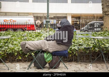 I senzatetto si avvolse per mantenere caldo, dormendo sulle sedie a Bryant Park lungo la 42nd Street nel centro di Manhattan, New York. Foto Stock