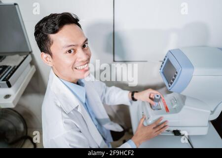 un medico di sesso maschile che utilizza un computer per gli occhi in una stanza Foto Stock