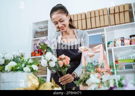 ritratto donna fiorista preparare un fiore regalo sul tavolo da lavoro Foto Stock