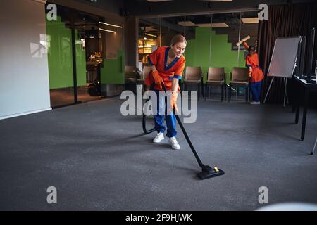 Personale di pulizia che utilizza uno scrubber in microfibra e un aspirapolvere Foto Stock