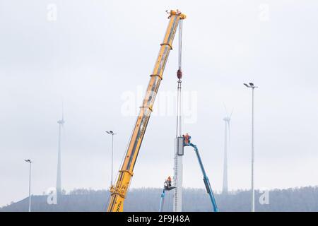 19 aprile 2021, bassa Sassonia, Osnabrück: I lavoratori montano il componente di una gru a portale con una gru speciale. Per l'espansione del terminale contenitore Osnabrück, si deve iniziare il lavoro di assemblaggio di due gru a portale larghe 50 metri e alte 40 metri. Il completamento del terminal dei container è previsto per l'estate. In futuro, ogni anno verranno trasferite fino a 150,000 unità di carico da strada a rotaia. Nel progetto sono stati investiti complessivamente 29 milioni di euro. Foto: Frito Gentsch/dpa Foto Stock