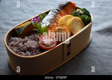 Wappa Bento, scatola per pranzo giapponese realizzata con piatto di legno rotondo, salmone alla griglia con sale Foto Stock