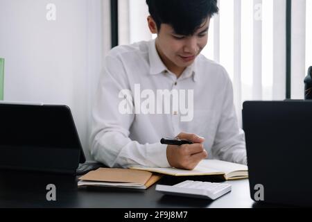 Uomo d'affari che tiene la penna e prende nota quando si incontra in ufficio Foto Stock