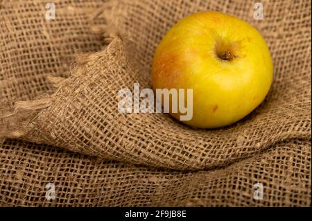 Mela verde fresca su un panno homespun con una consistenza ruvida. Messa a fuoco selettiva in primo piano. Foto Stock