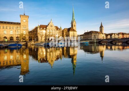 Il centro storico della città di Zurigo con il municipio, le chiese di Fraumunster e San Pietro che si riflettono nel fiume Limmat alla luce del mattino presto, Foto Stock