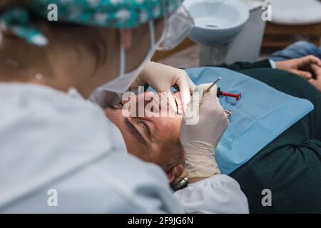 Dentista femminile con un paziente nel suo ufficio. Paziente con bocca aperta e donna dentista di lavoro. Concetto di salute dentale. Foto Stock