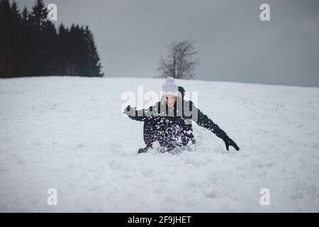 L'atleta cade da uno snowboard di plastica e cade duro sulla neve e gli sprawls. Inventare le assurdità nella quarantena nella neve. Cavalcare su una convenzione Foto Stock