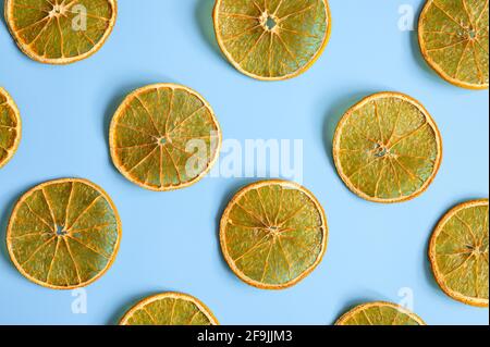 pezzi di arance a fette rotonde luminose, essiccate a scatti, su sfondo blu a contrasto, motivo ricorrente. disposizione piatta, vista dall'alto Foto Stock