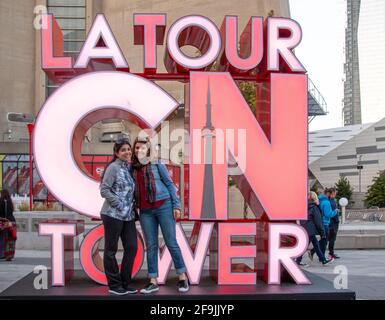 I turisti che hanno la loro foto scattata all'insegna della CN Tower, Toronto, Canada Foto Stock