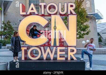 I turisti che hanno la loro foto scattata all'insegna della CN Tower, Toronto, Canada Foto Stock