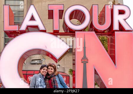 I turisti che hanno la loro foto scattata all'insegna della CN Tower, Toronto, Canada Foto Stock