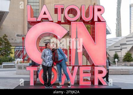 I turisti che hanno la loro foto scattata all'insegna della CN Tower, Toronto, Canada Foto Stock