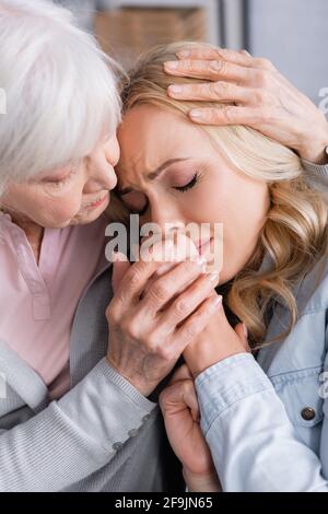 Donna anziana abbracciando e calmando sconvolto figlia Foto Stock