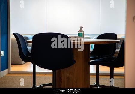 Ufficio in tempi di covid - disinfettante per le mani e tessuti al tavolo di riunione Foto Stock