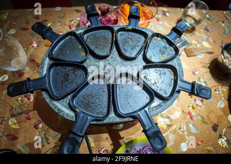 il tavolo della cena per famiglie condivide il cibo sulla raclette Foto Stock