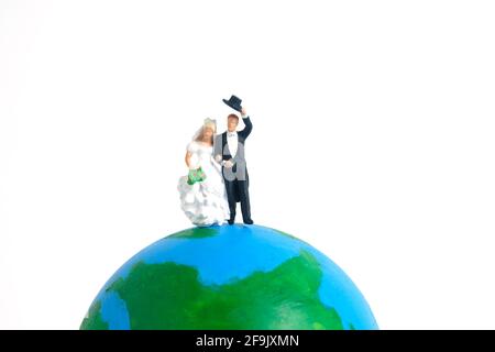 Matrimonio matrimonio giorno del mondo concettuale miniatura persone giocattolo fotografia. Sposa e sposo in piedi sopra il globo. Foto immagine Foto Stock