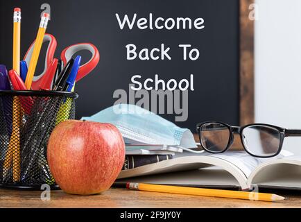 Scrivania della scuola con testo Welcome Back to School scritto sulla lavagna in background Foto Stock