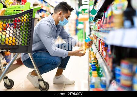 L'uomo medio-orientale che fa la spesa della groceria che sceglie l'olio di cottura in supermercato Foto Stock