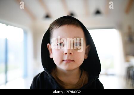 Povero ragazzo triste con sopracciglia tagliata in piedi in casa, concetto di povertà. Foto Stock