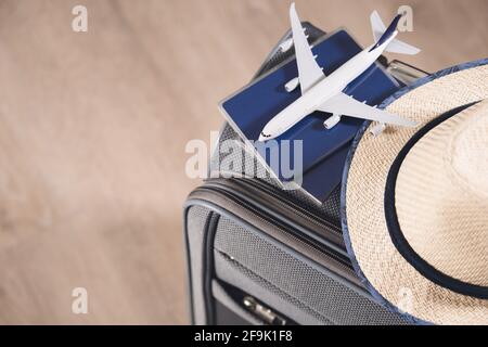 Stile di vita e concetto di viaggio dopo la quarantena passaporti, cappello e modello di aereo su valigia grigia Foto Stock