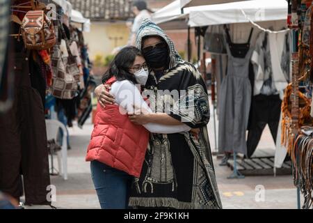 una coppia innamorata abbracciata nel mezzo di un mercato artigianale, l'uomo indossa un poncho e la donna un gilet, entrambi indossare maschere, nuova modernità Foto Stock