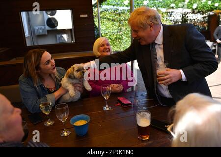 Il primo ministro Boris Johnson ha fatto animali domestici al cane di un cliente nella birreria all'aperto durante una visita al pub e ristorante Mount a Wolverhampton, West Midlands, sulla pista elettorale locale. Data immagine: Lunedì 19 aprile 2021. Foto Stock