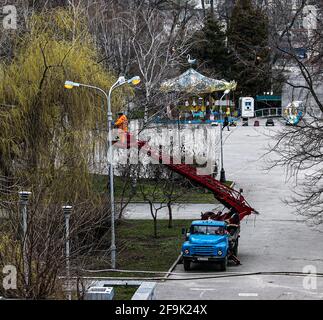 Dnepropetrovsk, Ucraina - 04.12.2021: Un operaio comunale in dispositivi di protezione che sostituisce le lampadine in una lampada da strada. Un lavoratore che ripara una lampada di strada di un bu Foto Stock