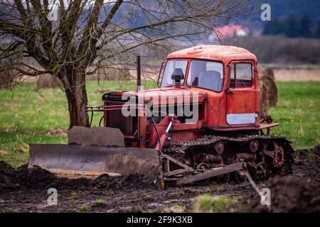 Un vecchio bulldozer caterpillar durante il lavoro di livellamento del terreno. Prodotto in una giornata nuvolosa, condizioni di scarsa illuminazione Foto Stock