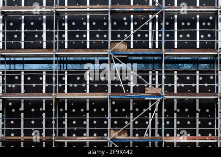 Impalcatura sulla parete di un edificio pubblico di nuova costruzione. Foto scattata con il tempo nuvoloso, nel tardo pomeriggio. Foto Stock
