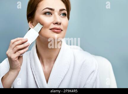 Peeling viso ultrasonico per il viso di una donna con scrubber ultrasonico. Pulizia della pelle del viso Foto Stock