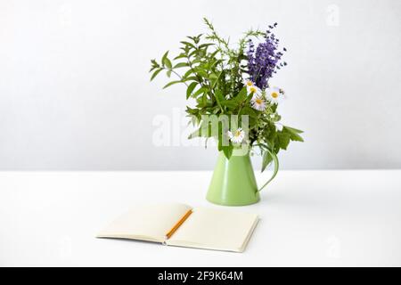 taccuino con matita e mazzo di fiori in caraffa Foto Stock