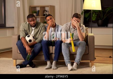 amici maschi tristi o tifosi di calcio con birra a casa Foto Stock