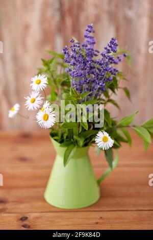 mazzo di erbe e fiori in caraffa verde sul tavolo Foto Stock