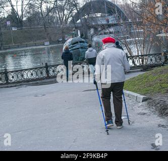 Dnepropetrovsk, Ucraina - 03.21.2021: Donna stanca di età matura cammina per la città. Una donna tiene in mano bastoni nordici da passeggio. Foto Stock