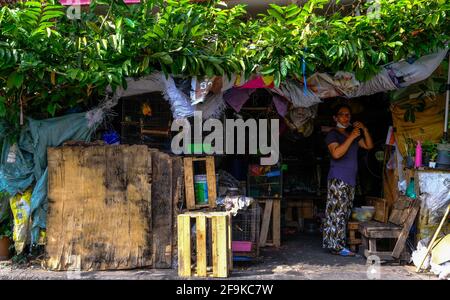 Una donna accende una sigaretta all'interno dei suoi locali in una piccola strada a Bangkok, Thailandia. Foto Stock