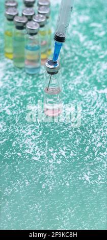 Prevenzione delle malattie stagionali. Fiale mediche, siringhe e una maschera su sfondo verde. Vaccinazione contro covid-19. Foto Stock